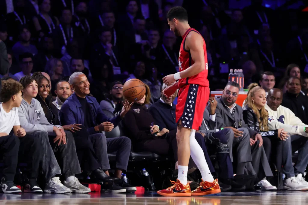 Barack Obama catches a loose basketball courtside at the 2026 NBA All-Star Game to protect Michelle Obama.