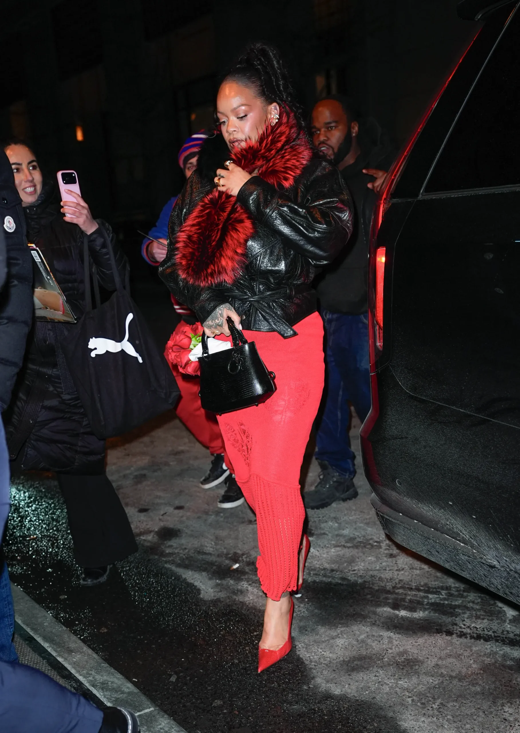 Rihanna in NYC wearing a red John Galliano knit dress, an ERL cropped leather jacket, and a Dolce & Gabbana fur scarf.